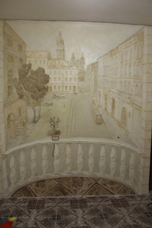 площа ринок Львів . Техніка виконання художня ліпнина, барельєф виконується безпосередньо на стіні із якісних сучасних матеріалів, декоративних штукатурок. Спочатку ліпиться барельєф, а потім тонується лаком або воском із пігментами. 